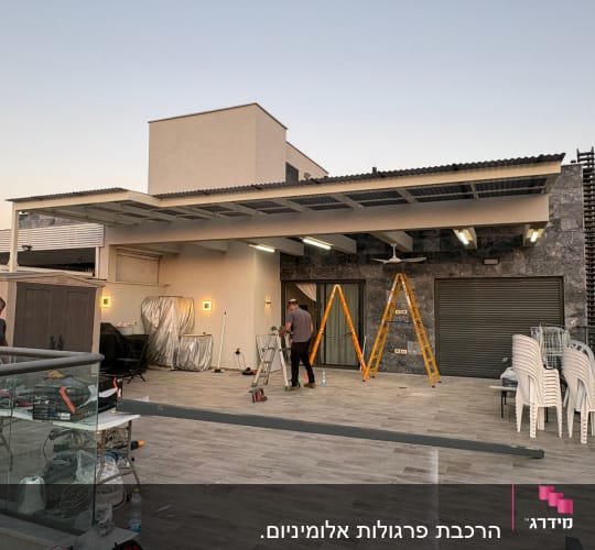 התקנת פרגולה מאלומיניום על גג עם סולמות וכלים